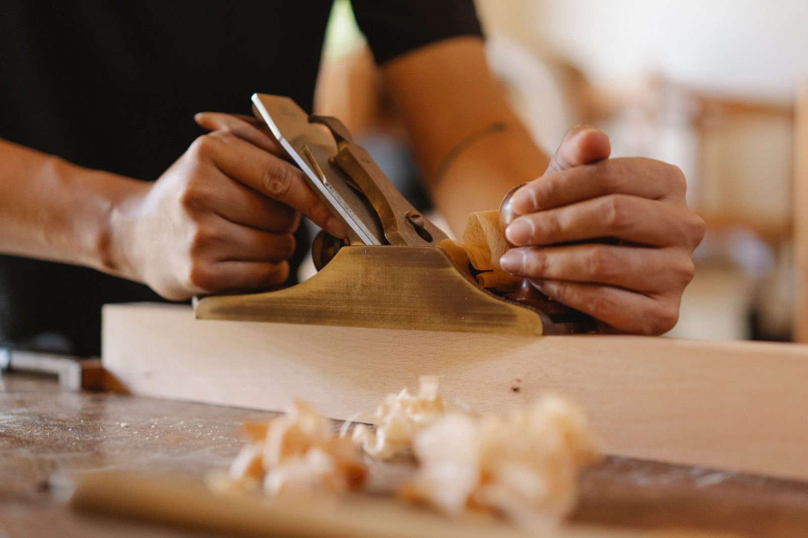 Ein Tischler bearbeitet in seiner Werkstatt ein Brett mit der Handmaschine