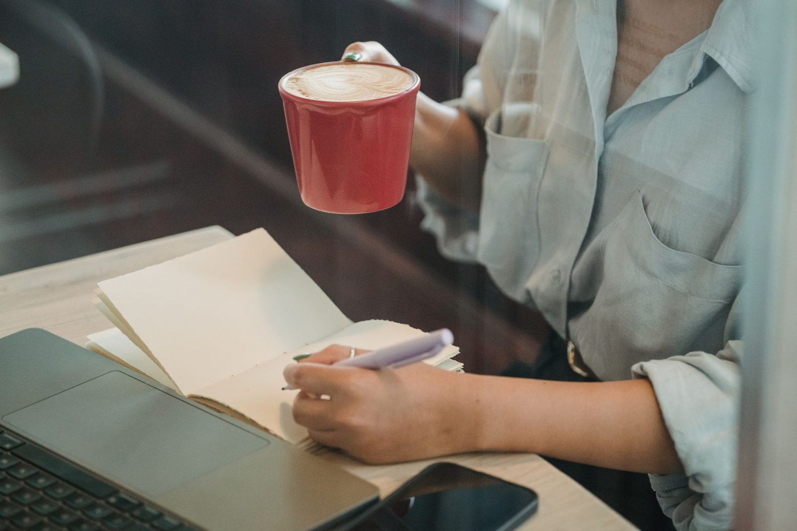 Eine Frau schreibt in ein Notizbuch in einem Café